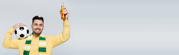 Cheerful sports fan with beer and soccer ball smiling at camera isolated on grey, banner — Stockfoto