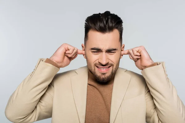 Displeased critic plugging ears with fingers isolated on grey — Stock Photo