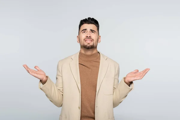 Upset critic looking up while standing with open arms isolated on grey — Stock Photo