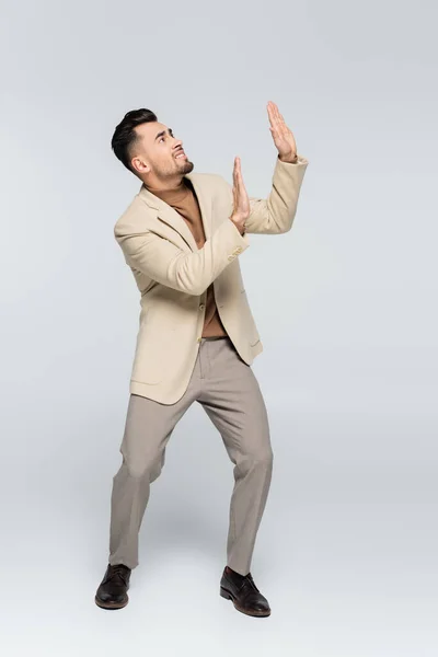 Full length of worried critic looking up and showing stop gesture on grey — Stock Photo