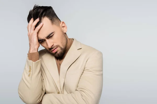 Depressed critic in beige blazer touching head isolated on grey — Stock Photo