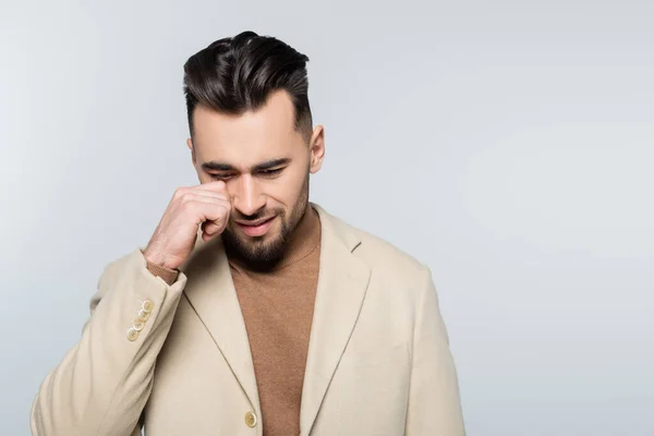 Young upset critic wiping eye while crying isolated on grey — Stock Photo