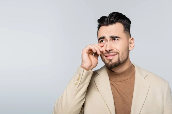 Stressed critic looking away and crying isolated on grey - foto de stock