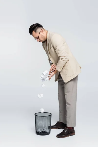 Visão de comprimento total do crítico jogando papel enrugado em lata de lixo em cinza — Fotografia de Stock