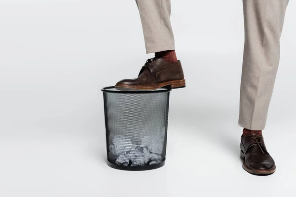 Cropped view of critic stepping on trash can with crumpled paper on grey — Fotografia de Stock