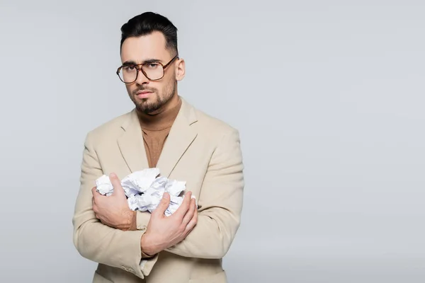 Upset critic in eyeglasses looking at camera while holding crumpled paper isolated on grey — Foto stock