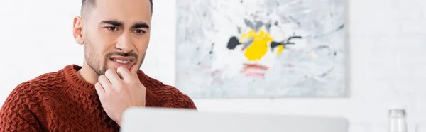 Nervous bookmaker touching face and looking at blurred laptop, banner — Stock Photo