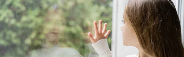 Girl looking through window and touching glass with raindrops, banner — Stock Photo