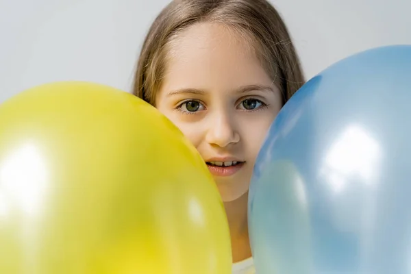 Patriotisches Mädchen blickt in die Kamera in der Nähe blauer und gelber Luftballons isoliert auf grau — Stockfoto