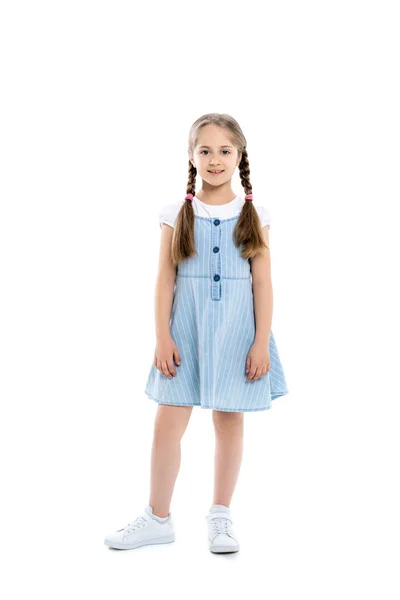 Повний вигляд дівчини в синій сукні ремінця, посміхаючись на камеру, стоячи на білому — стокове фото