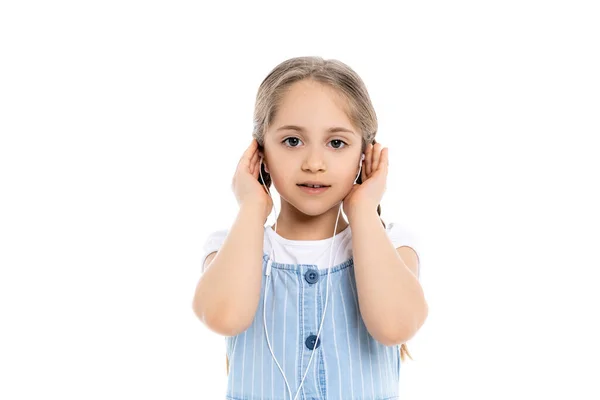Дівчина дивиться на камеру і налаштовує навушники ізольовані на білому — стокове фото