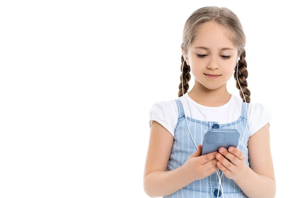 Menina positiva em fones de ouvido com fio usando telefone celular isolado no branco — Fotografia de Stock