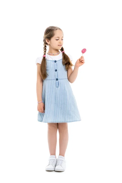 Full length view of girl in blue strap dress looking at lollipop on white — Stock Photo