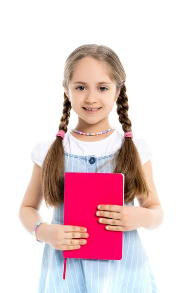 Mädchen mit Zöpfen hält leuchtend rosa Notizbuch und lächelt in die Kamera isoliert auf weiß — Stockfoto