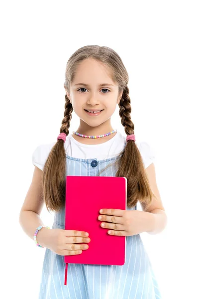 Girl with braids holding bright pink notebook and smiling at camera isolated on white — Stock Photo