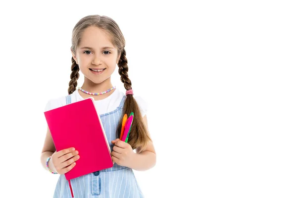 Menina alegre com canetas de feltro coloridas e livro de cópia olhando para a câmera isolada no branco — Fotografia de Stock