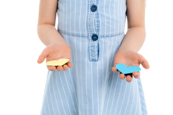 Vue partielle de fille tenant des coeurs en papier bleu et jaune isolés sur blanc — Photo de stock