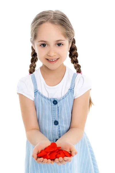 Cheerful child showing handful of red toy hearts isolated on white — Stock Photo