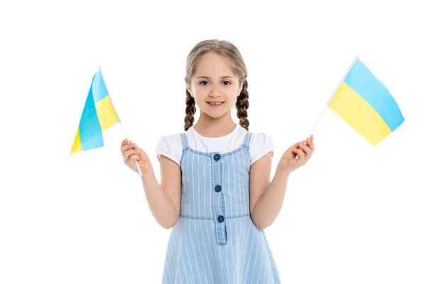 Chica feliz con pequeñas banderas ucranianas sonriendo a la cámara aislada en blanco - foto de stock