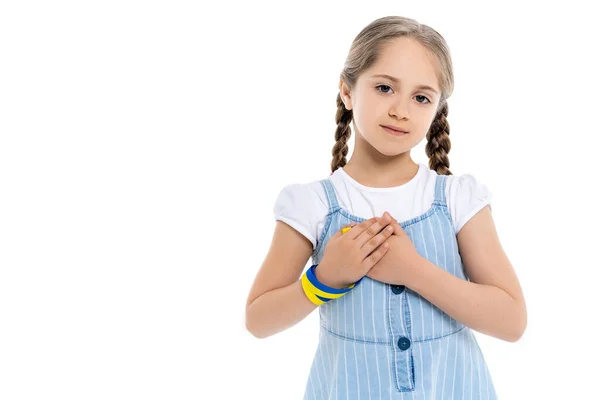 Ukrainian girl with blue and yellow patriotic ribbon touching heart isolated on white — Stock Photo