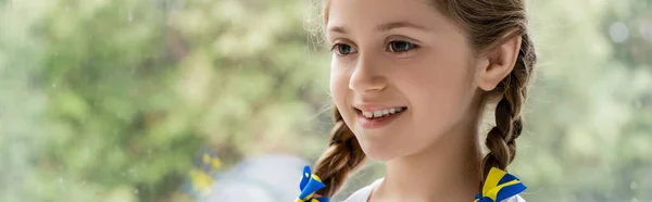 Portrait of happy ukrainian girl with blue and yellow ribbons on braids, banner — Stock Photo