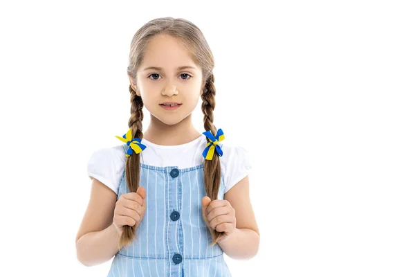 Menina patriótica com fitas azuis e amarelas em tranças olhando para a câmera isolada no branco — Fotografia de Stock