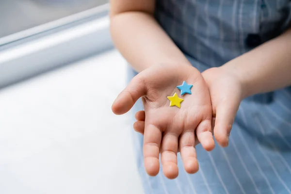 Partial view of child with blue and yellow stars on open palm — Stock Photo