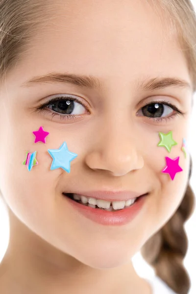 Primer plano retrato de chica alegre con estrellas de colores en la cara sonriendo a la cámara aislada en blanco - foto de stock