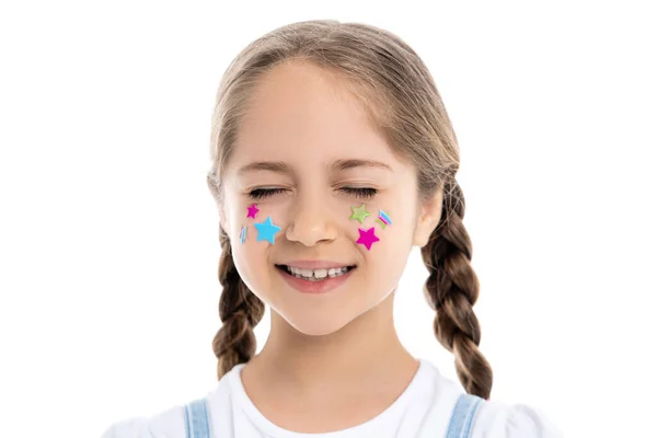 Menina com olhos fechados e estrelas multicoloridas no rosto sorrindo isolado no branco — Fotografia de Stock