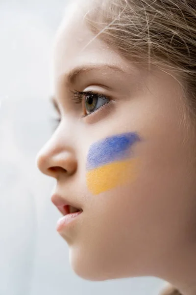 Close up portrait of patriotic girl with ukrainian flag on face on white background — Stock Photo