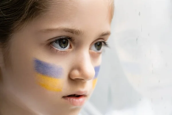 Close up retrato de criança ucraniana com bandeiras nacionais no rosto no fundo branco — Fotografia de Stock