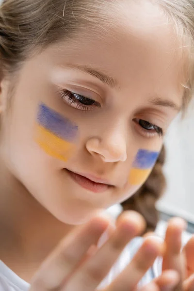 Primer plano retrato o chica patriótica con banderas ucranianas pintadas en la cara - foto de stock