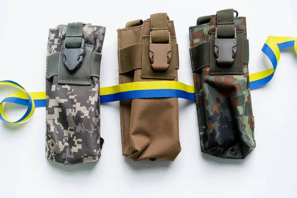 Vue du dessus du ruban bleu et jaune sur les sacs militaires sur fond blanc — Photo de stock