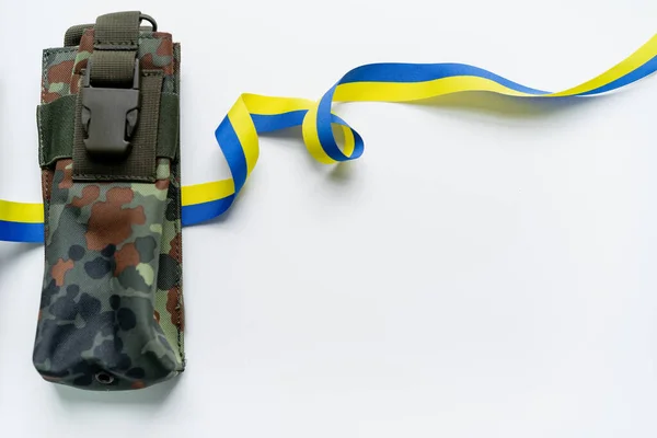 Top view of blue and yellow ribbon near military bag on white background — Stock Photo