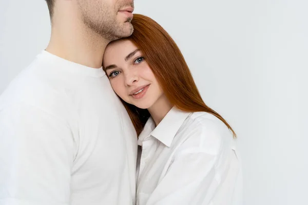 Souriant rousse femme regardant la caméra près du petit ami isolé sur blanc — Photo de stock