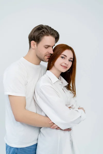 Jeune homme étreignant souriant rousse petite amie isolé sur blanc — Photo de stock