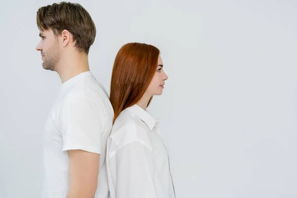 Vista lateral do jovem casal de pé de costas para trás isolado no branco — Fotografia de Stock