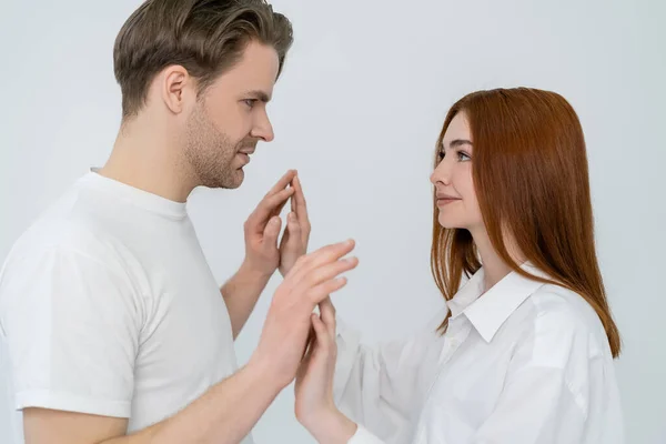 Side view of young couple looking at each other and touching hands isolated on white — Stock Photo