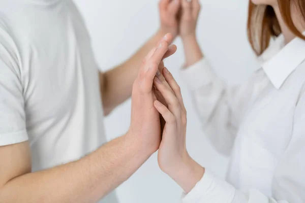 Vista recortada de pareja borrosa tocando las manos aisladas en blanco - foto de stock