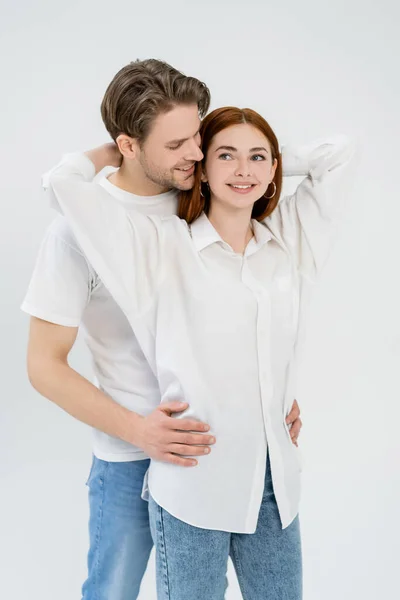 Sorridente uomo abbracciando rossa ragazza isolata su bianco — Foto stock