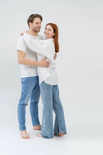 Full length of young barefoot woman embracing boyfriend on white background — Stock Photo