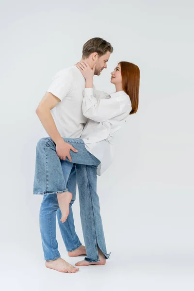 Seitenansicht eines jungen Paares, das sich auf weißem Hintergrund anschaut — Stockfoto
