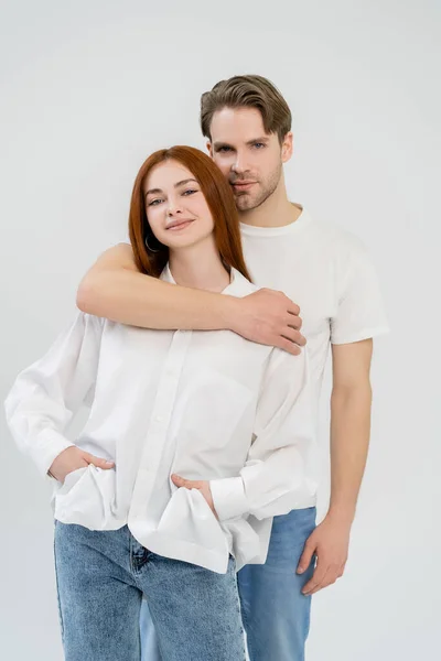 Jeune homme étreignant petite amie rousse en chemise isolée sur blanc — Photo de stock