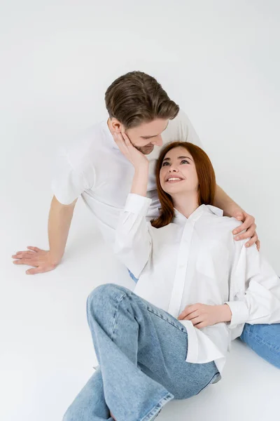 High angle view of smiling woman in shirt touching boyfriend on white background — Stock Photo