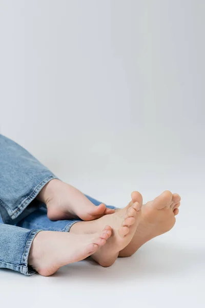 Cropped view of barefoot couple in jeans on white background — Stock Photo