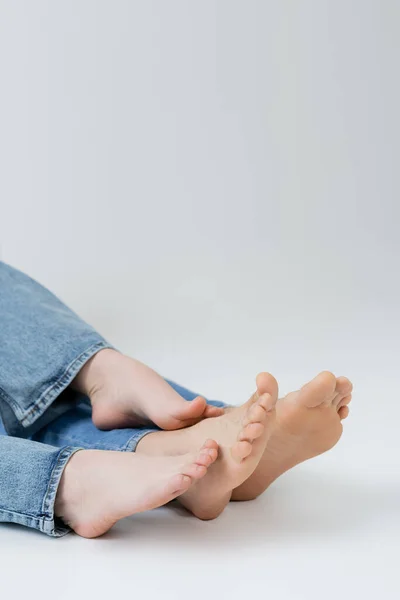 Vista cortada de casal descalço em jeans no fundo branco — Fotografia de Stock