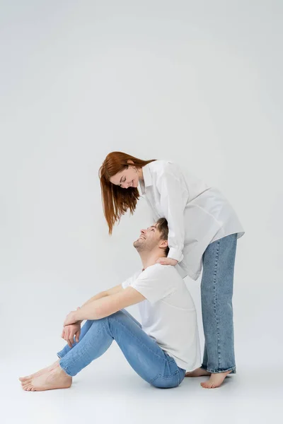 Mulher alegre na camisa olhando para o namorado no fundo branco — Fotografia de Stock