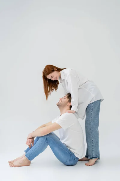 Cheerful woman in shirt looking at boyfriend on white background — Stock Photo