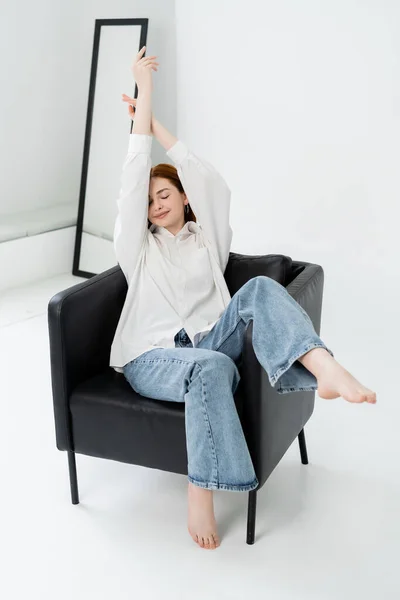 Pretty barefoot woman sitting on armchair on white background — Stock Photo