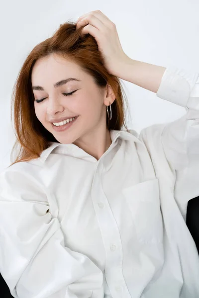 Mujer pelirroja feliz en camisa ojos cerrados aislados en blanco - foto de stock